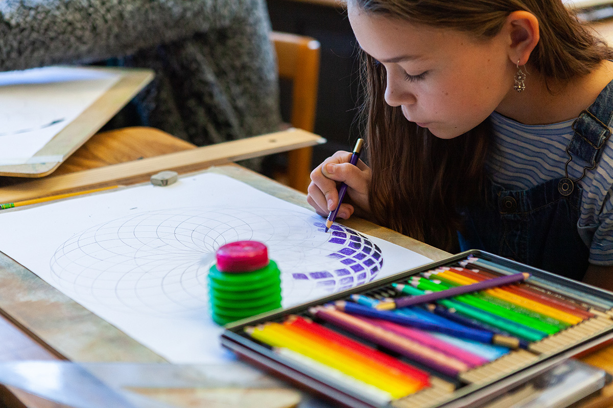 A 6th grade student uses colored pencils to color in an intricate geometric pattern